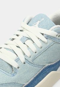 Baskets en denim bleu clair avec lacets blancs, col rembourré et logo Jumpman blanc sur la languette.