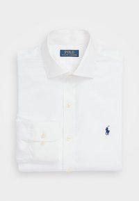 Valkoinen pitkähihaisten paita, taiteltu siististi, nappikuppi ja sinisellä brodeeratulla polo-pelaajan logolla rinnassa.