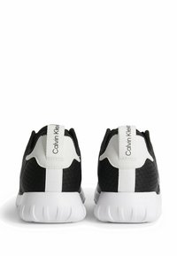 Svarta mesh-sneakers med vita accenter, som har en slät sula och uttalad klack, märkta med "Calvin Klein" på baksidan av fliken.