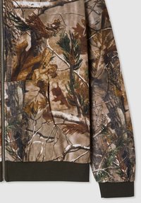 Giacca zip-up mimetica con una combinazione di colori marrone, verde e sabbia. Presenta una tasca frontale e polsini e orlo a coste. Texture del tessuto morbida.