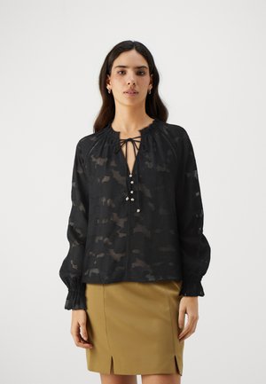 Black sheer blouse with floral pattern, deep V-neck, tie detail, and button embellishments. Features gathered cuffs and loose fit.