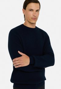 Granatowy sweter z prążkowanego dzianiny z okrągłym dekoltem i długimi rękawami, o luźnym kroju i teksturowanej tkaninie, idealny na co dzień.