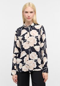 Blouse à manches longues en navy avec un motif floral en rose clair et crème. Dispose d'un col et de boutons noirs sur le devant. Texture de tissu lisse.