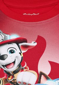 Rotes Kurzarmhemd mit einem Grafik eines Cartoon-Hundes in Feuerwehruniform. Das Material ist glatt mit lebendigen Farben und kräftigen Umrissen.