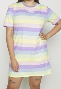 Robe à manches courtes à rayures pastel dans des tons de lavande, jaune et menthe. Fabriquée dans un tissu doux, avec un col rond et un détail logo.