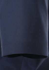 Marineblauer Stoffabschnitt mit glatter Textur und geradem Saum, der eine präzise Stickerei entlang der Kante zeigt.