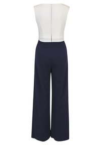 Top de combinaison blanche avec un corsage ajusté, pantalons larges navy, et une fermeture éclair au dos. Tissu lisse, sans motifs ni accents visibles.