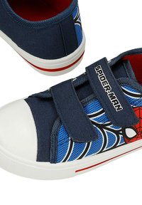 Baskets bleu marine pour enfants avec embouts en caoutchouc blanc, bande rouge sur les semelles, motif toile d’araignée Spider-Man et deux bandes velcro marquées Spider-Man.