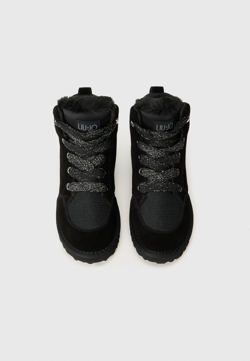 Bottines noires en cuir suédé et en mesh. Elles possèdent une doublure en fourrure douce, des lacets texturés et une semelle en caoutchouc.