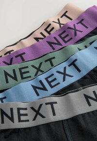 Fyrpack med elastiska midjeband i svart, grått, blått, grönt och lila, med iögonfallande "NEXT"-logga på varje band.