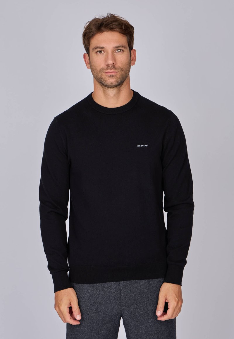 Pull en tricot noir avec un col rond, des manches longues et un logo subtil sur la poitrine. Dispose d'un ourlet et de poignets côtelés.