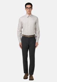 Pruhovaná košile světle šedé a bílé barvy, kombinovaná s tmavě šedými kalhotami a hnědým pásem. Obuv zahrnuje hnědé semišové boty.