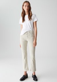 Witte crewneck t-shirt, lichtbeige corduroy broek met een rechte snit en zwarte instapschoenen. Gladde textuur, geen zichtbare patronen of accenten.