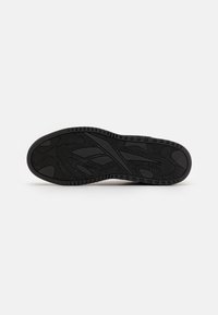 Black rubber shoe sole with textured pattern and defined tread for traction. Features grooves and raised areas for improved grip.