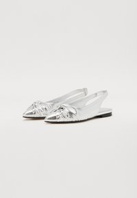 Ballerines argentées métalliques à bride arrière avec un bout pointu et un détail noué à l'avant, présentant un design épuré et un petit talon noir.