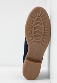 Suela de zapato de ante azul oscuro con una banda de rodadura de goma color tan que presenta un patrón ondulado y un logo estampado. Talla 37 marcada en el lateral.