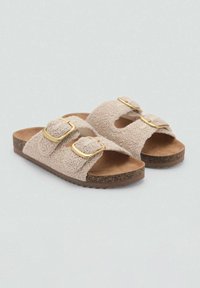Sandales tressées beiges avec deux boucles dorées réglables, tige texturée et semelle en liège brun pour la solidité et le confort.