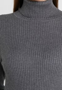 Grijze ribgebreide coltrui met een nauwsluitend ontwerp, featuring een hoge hals en verticale textuur door de stof.