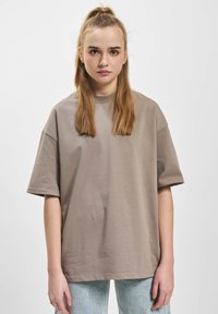 Oversized, short-sleeve t-shirt in muted taupe cotton. Straight hemline and crew neck. Paired with light denim jeans.