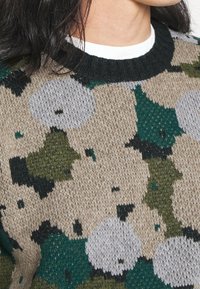 Strickpullover mit einem Camouflage-Muster in den Farben Grün, Beige und Grau; runder Ausschnitt und strukturierter Gewebemuster.