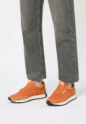 Sneaker arancioni con un mix di materiali in camoscio e rete, con una suola intermedia bianca e una suola in gomma nera. Design con lacci e accenti del logo.