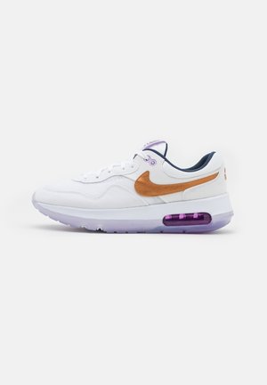 Białe sneakersy z beżowymi i fioletowymi akcentami. Posiadają chropowaty materiał wierzchni, wiązanie na sznurówki i widoczną jednostkę powietrzną w podeszwie.