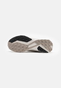 Sneaker-Sohle aus Gummi mit einem robusten Muster; verfügt über einen schwarzen strukturierten Bereich und eine hellgraue Farbgebung mit kantigen Akzenten.
