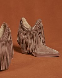 Botines con flecos en ante marrón claro, con punta afilada, tacón apilado y costuras decorativas a lo largo del borde superior.