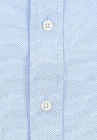 Lichtblauwe textuurshirt met knoopsluiting. Bevat subtiele diagonale strepen en een gladde stofafwerking. Witte knopen met vier gaten.