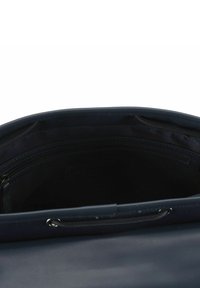 Innenraum einer marineblauen Lederhandtasche mit glatter Textur, mehreren Reißverschlusstaschen und einem einzelnen offenen Fach.