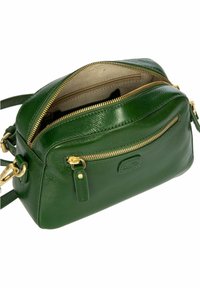 Sac à dos en cuir vert avec quincaillerie dorée, surface texturée, compartiments zippés et sangle réglable. Comprend une poche avant.