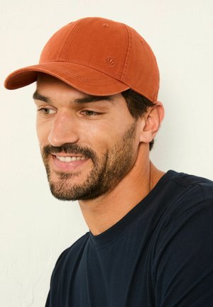 Rust-colored baseball cap with a curved brim. Made of textured fabric, featuring stitching details and a logo accent on the side.