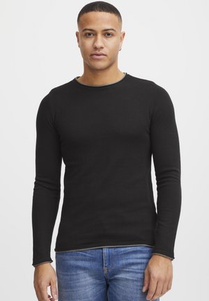 Black long-sleeve shirt with a round neck, made of soft fabric, featuring a contrasting green trim along the neckline and cuffs.