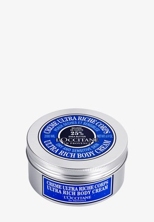 Behållare av L'Occitane Ultra Rich Body Cream med 25 % sheasmör, märkt för torr och känslig hud, 200 ml i en rund silverburk med blå accenter.