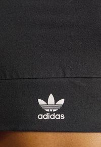 Czarny dopasowany top na ramiączkach wykonany z elastycznej tkaniny, z białym logo Adidas i trzema paskami u dołu stanowiącymi element identyfikacji marki.