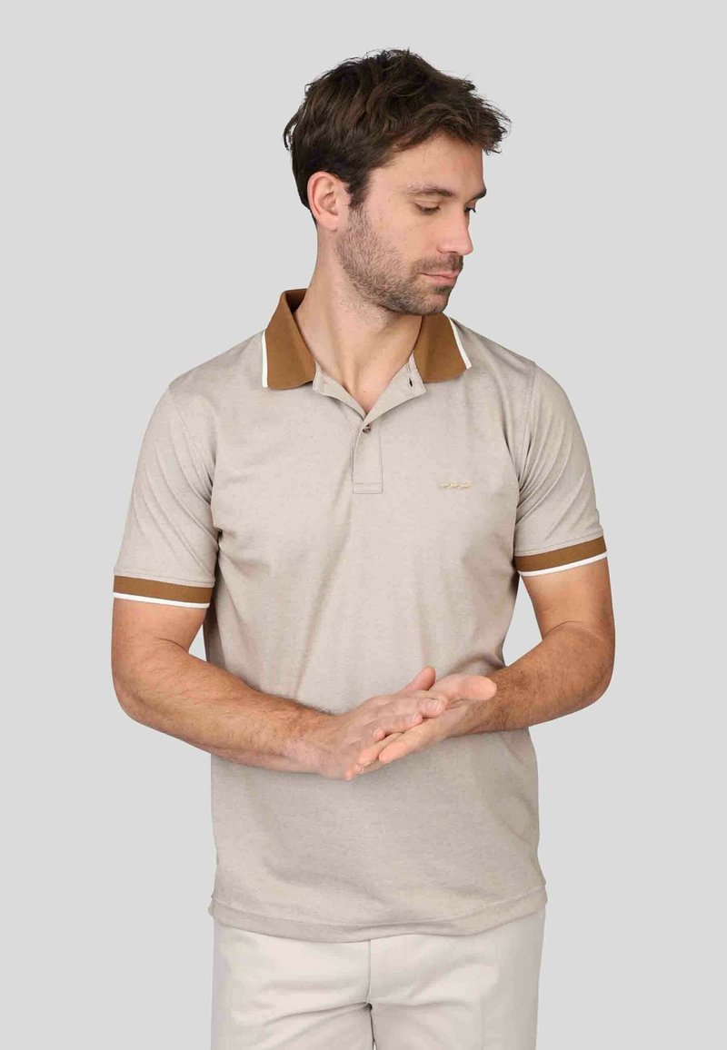 Polo beige avec un col et des accents de manches bruns, doté d'une patte de boutonnage à deux boutons, d'un liseré blanc et d'un logo discret sur la poitrine.