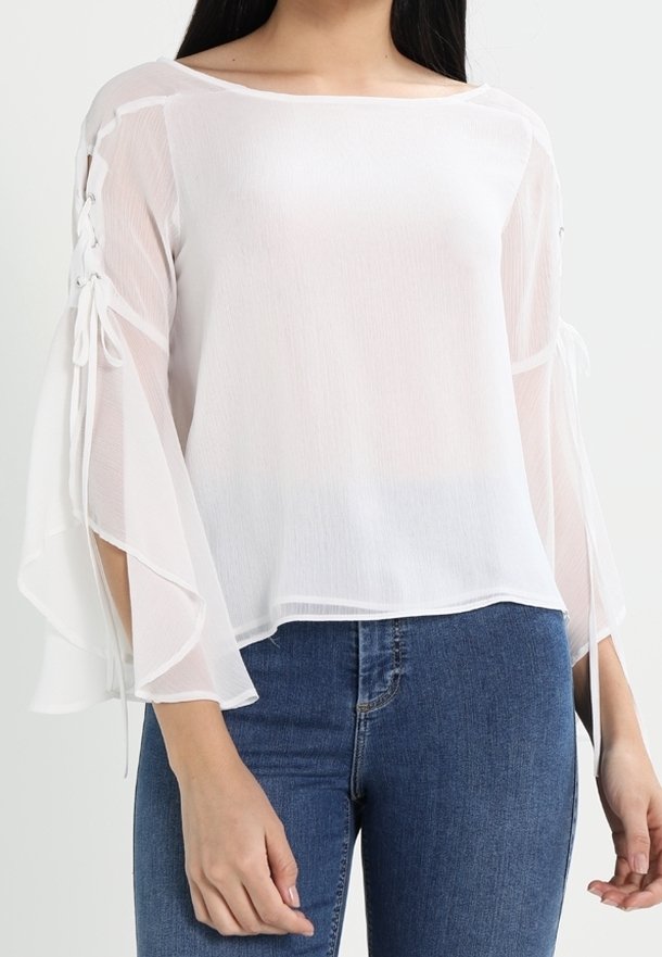 Blusa bianca leggera con maniche a campana flottanti e dettaglio con lacci ai polsini, caratterizzata da una vestibilità rilassata e una texture morbida.