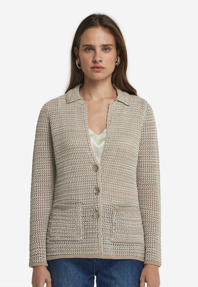 Beżowy szydełkowany kardigan z kołnierzykiem, przednimi kieszeniami i zapięciem na guziki. Teksturowany wzór dzianiny z luźnym krojem.
