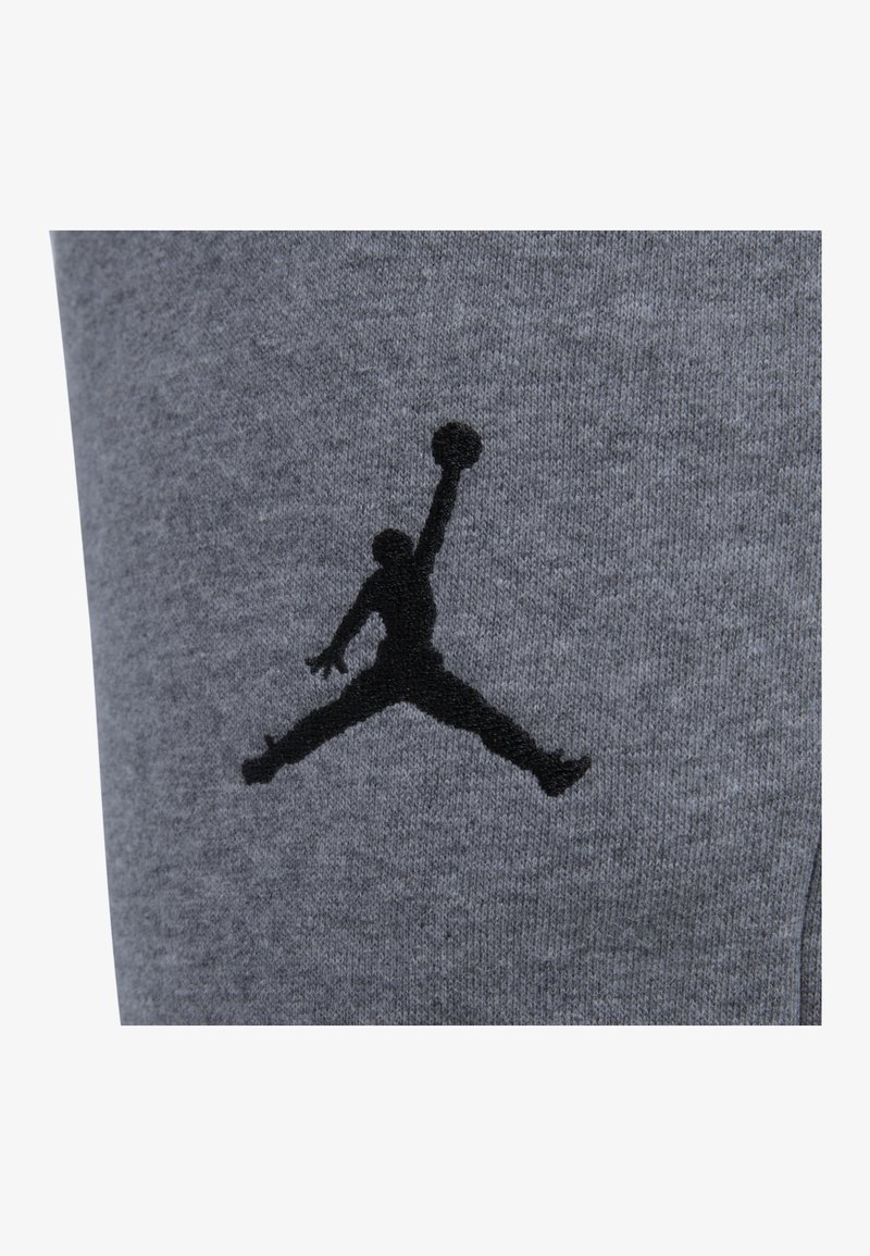 Szary materiał bluzy z kapturem z czarnym logo Jumpman, przedstawiającym sylwetkę gracza skaczącego z piłką koszykową.
