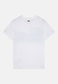 T-shirt en coton blanc avec un design simple, des manches courtes et un petit logo brodé près du cou à l'arrière. Texture douce.