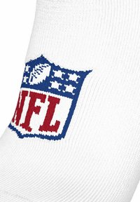 Hvid strikket stof med et blåt og rødt NFL-skjoldlogo, der har et mønster af en fodbold og stjerner.