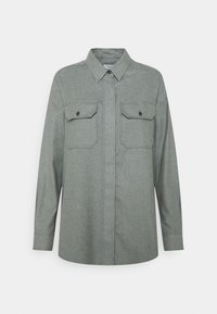 Camicia grigia a maniche lunghe realizzata in tessuto testurizzato, con un colletto classico, chiusura frontale con bottoni e due tasche sul petto con pattina e dettagli in bottone.