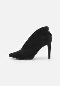Scarpa con tacco alto in suede nero, punta affusolata, dettaglio con zip lungo il lato, design elegante e tacco a stiletto sottile.