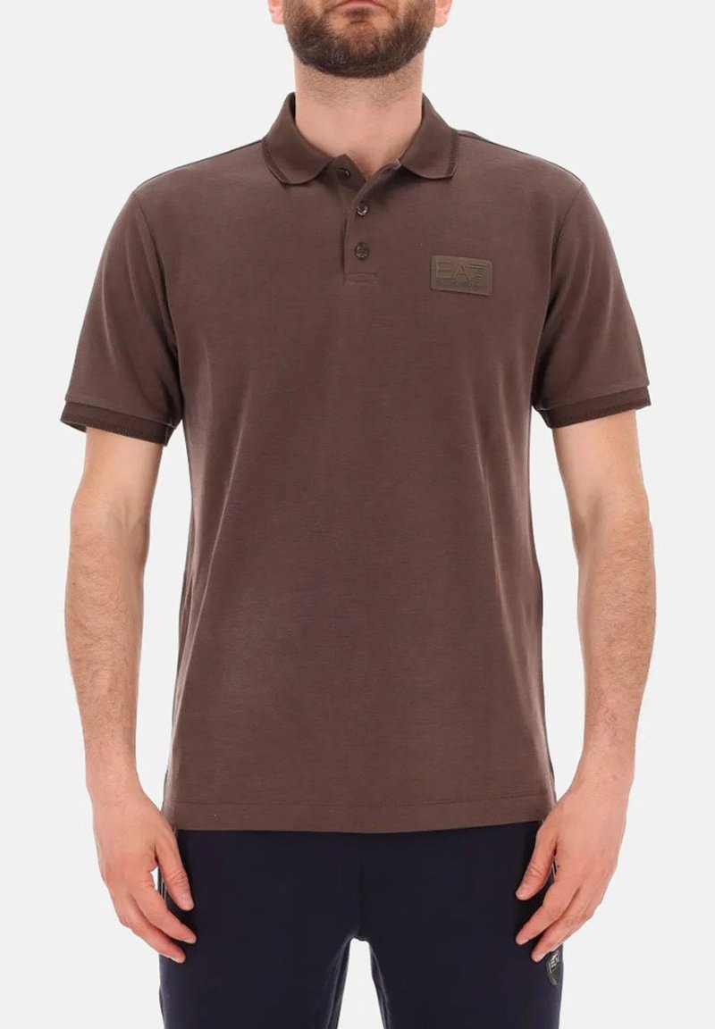 Polo shirt marrone realizzato in cotone, con colletto, tre bottoni e un'etichetta rettangolare sul petto sinistro.
