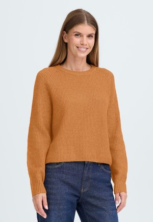 Ribbad orange tröja med långa ärmar och rund halsringning, parat med mörka jeans, har en avslappnad passform och en strukturerad yta.