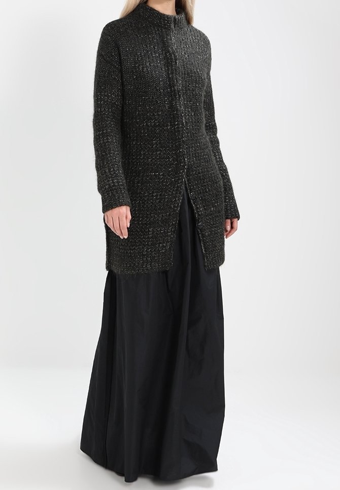 Long black skirt and a dark grey textured cardigan with a high neck, featuring a front button closure and side slits.