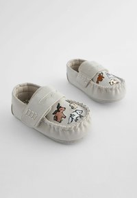 Light gray moccasin shoes with embroidered animal designs on the toe, featuring a Velcro strap and stitched edges. Soft material, flat sole.