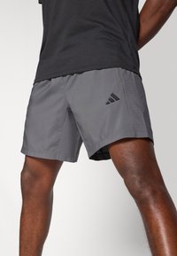 Γκρι αθλητικό σορτς με λείο, ελαφρύ ύφασμα, με πλευρικό αερισμό, μικρό μαύρο λογότυπο και ευθεία τελείωμα.