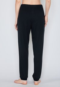 Zwarte, lichte, stretchbroek met een elastische tailleband, taps toelopende manchetten en een gladde textuur. Geen zichtbare zakken of patronen.