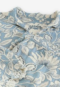 Blue floral-patterned fabric with cream accents, featuring large leaves and flowers, collared design, and delicate lace trim at the hem.